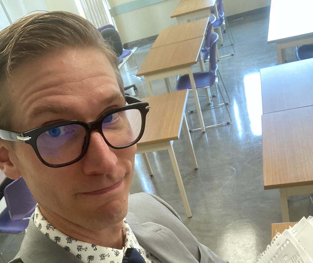 Nathan Dueck in a classroom with desks and chairs.