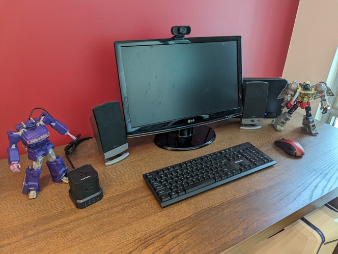 A desk with computer and Transformers figurines of Shockwave and Grimlock